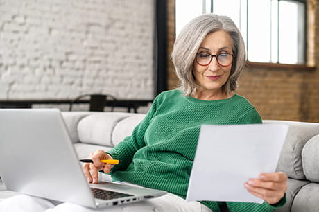 Woman in green sweather wearing reading glasses on computer