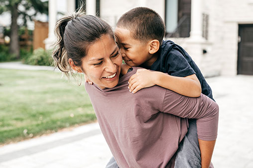 mother in her 30s giving son a piggy back ride