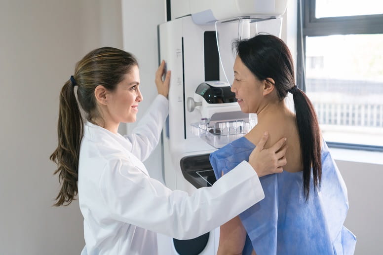 Female doctor helping a patient get in position for a mammogram