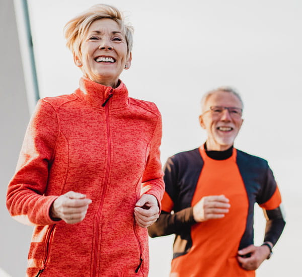 An active senior couple with joint replacements jogging