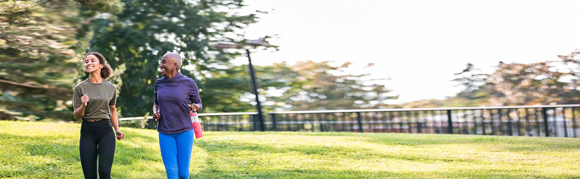 Two black women, a senior and a young woman, enjoying a jog outdoors. Both dressed in sporty clothes.