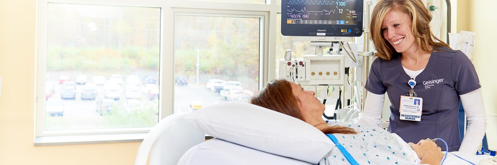 Healthcare provider smiling at patient laying in bed near window