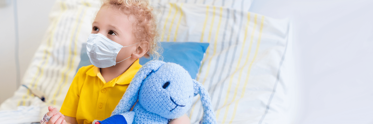 Child in bed wearing mask with stuffed animal