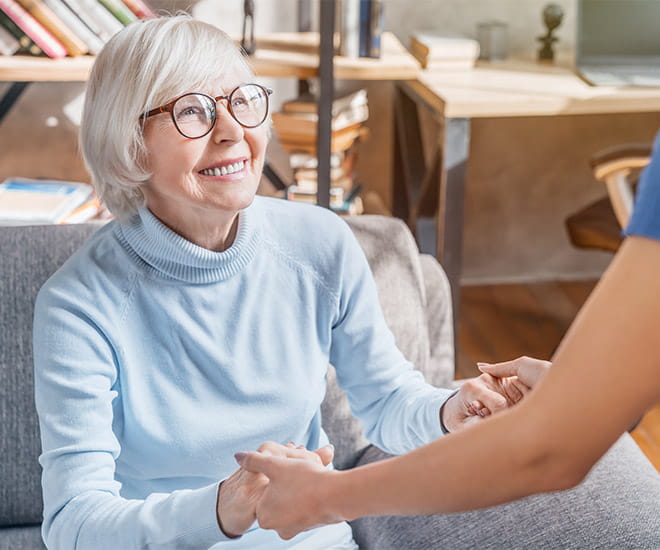 senior woman happily smiling at a nurse at home