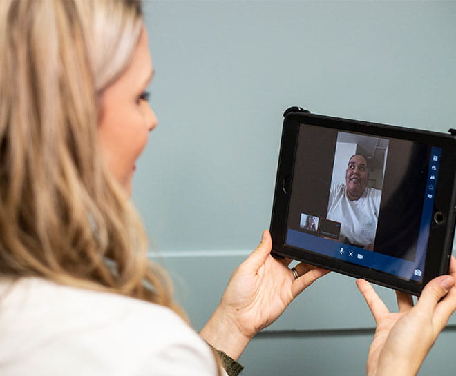 doctor holding an ipad with a patient doing a telehealth appointment