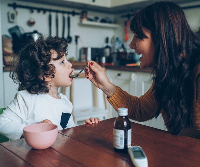 Mother giving medicine to her son