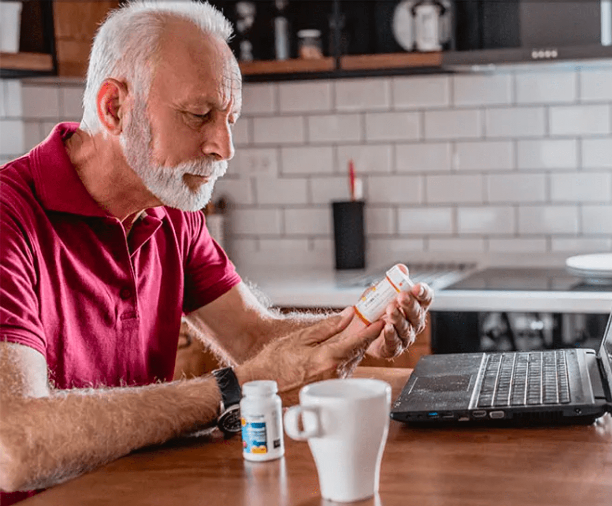 older man reading prescription at kitchen table