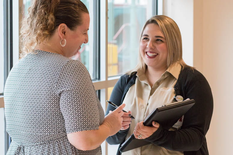 two women talking with clipboard