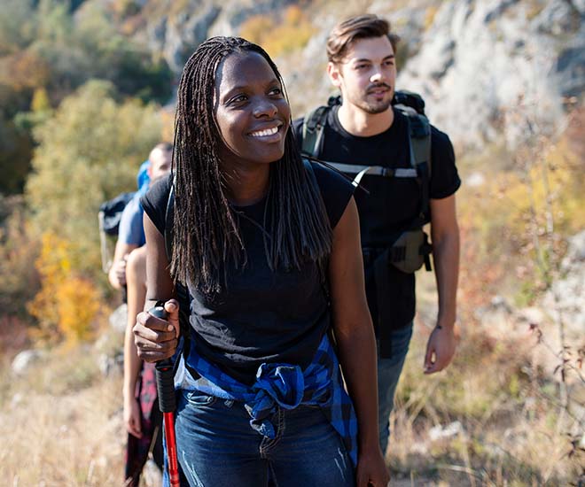 A group of young hikes in the woods begins their ascent up a hill.