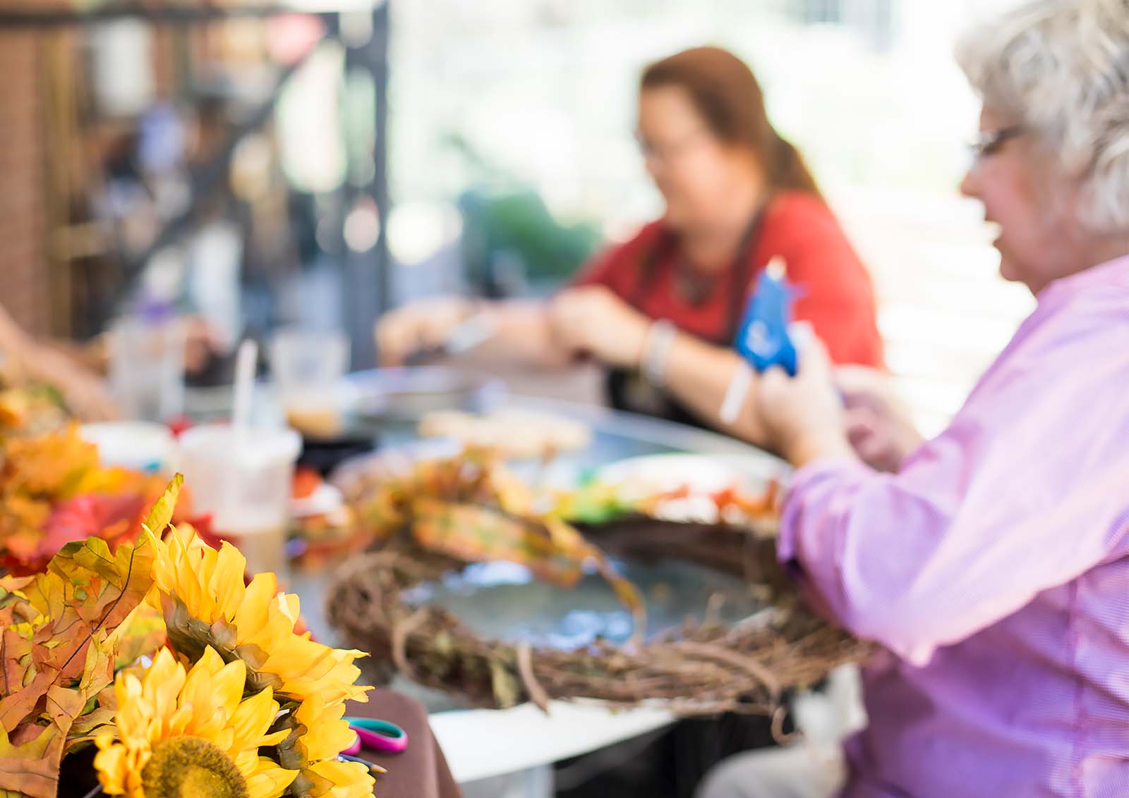 Two women creating floral wreaths in a crafting class.