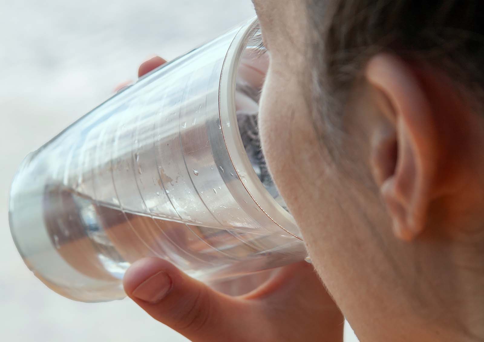 A young woman drinks water to help alleviate hiccups.
