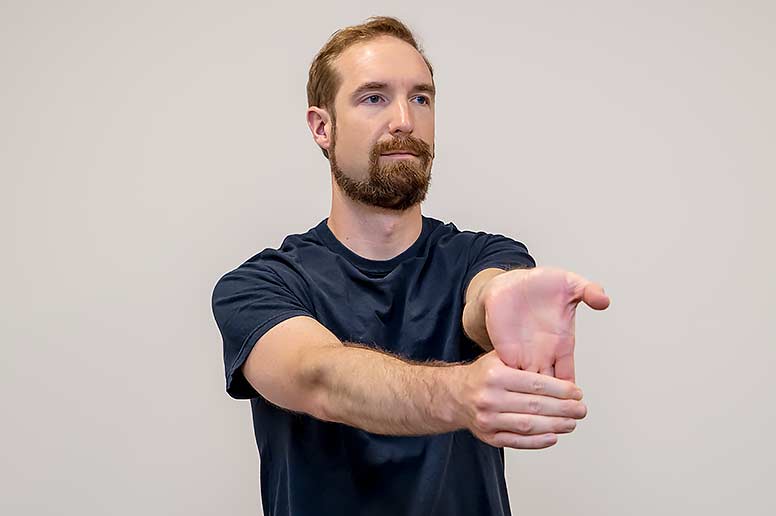 Performing a wrist flexor stretch.