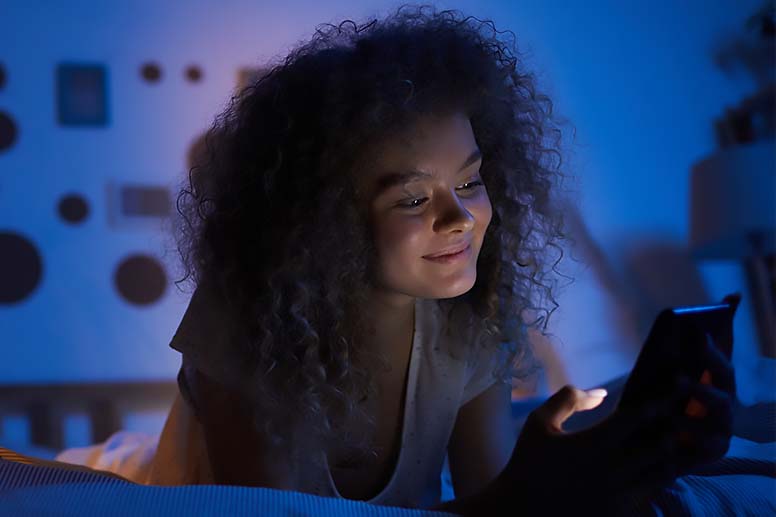 A teenager views content on her smartphone before bedtime.