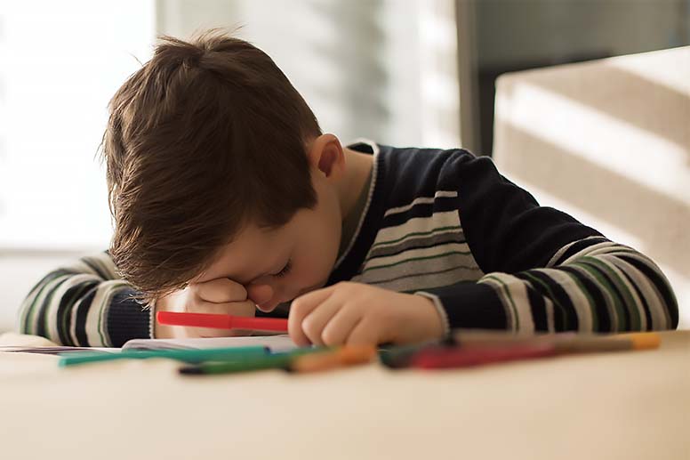 A young student falls asleep in the classroom.