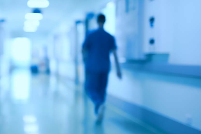 A hospital staff member walking alone in the hospital hallway.