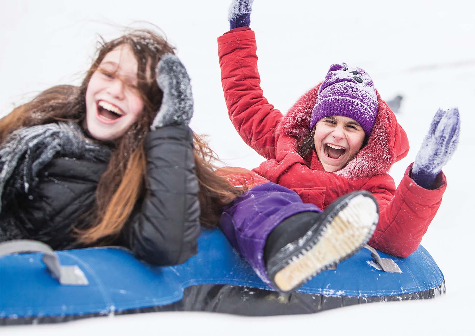 Young children enjoying snowtubing down a hill.