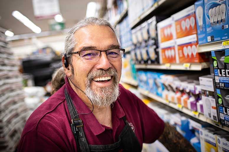 Smiling male worker stocking shelves at a store.