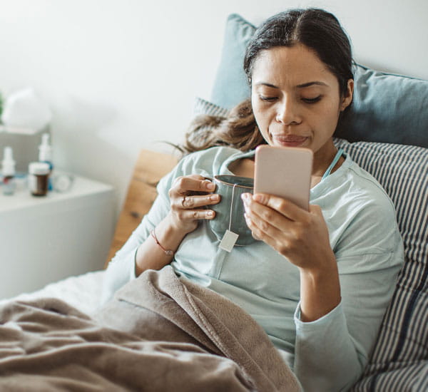 Woman in bed using phone