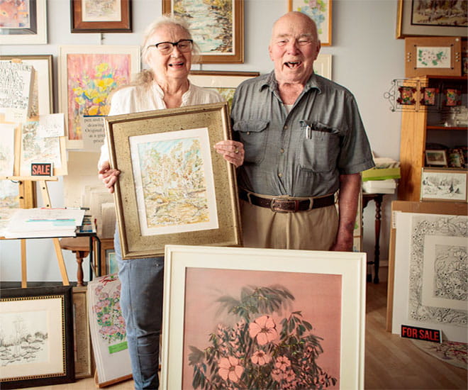 Happy senior couple surrounded by paintings.