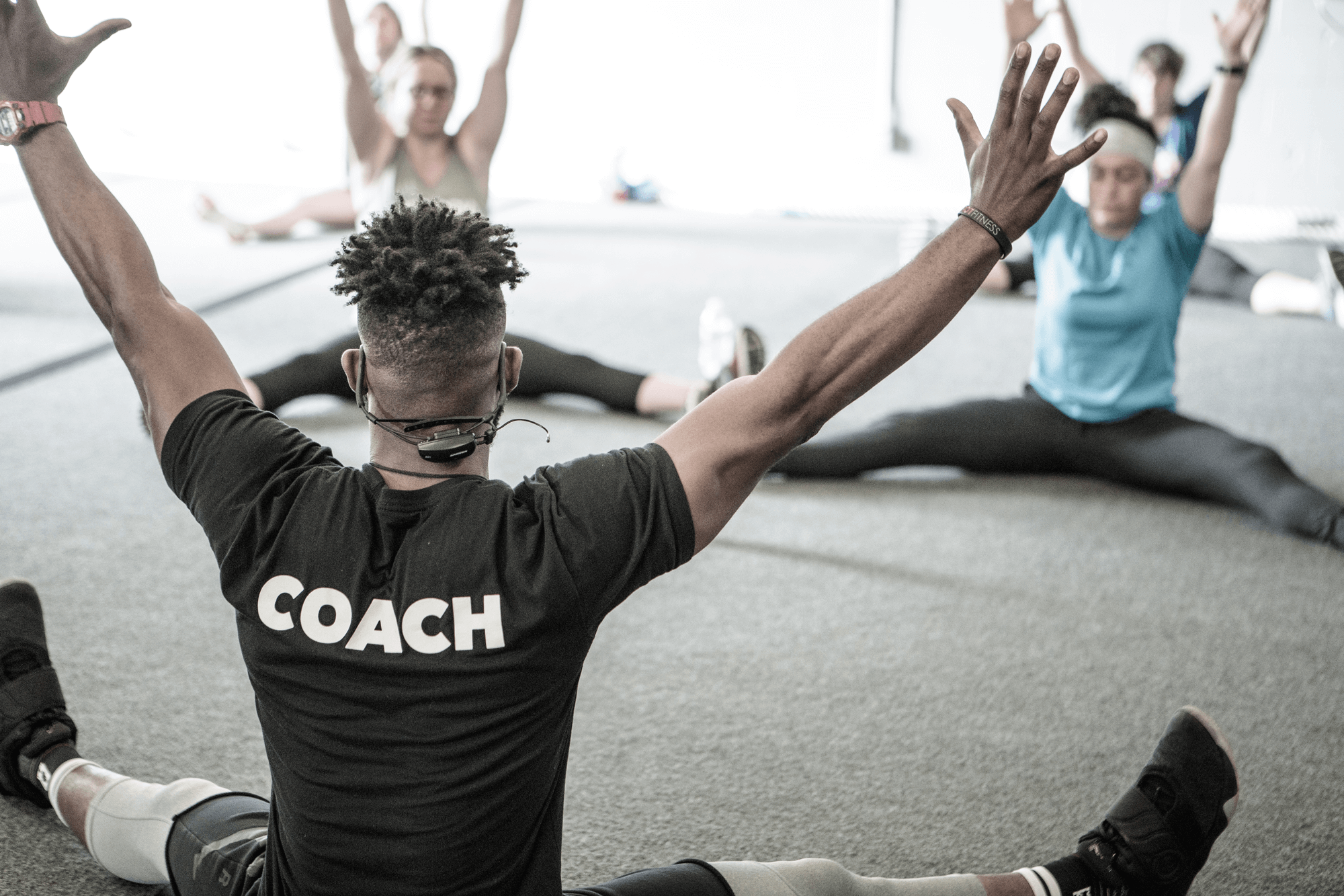 A gym coach works with several adults in a studio