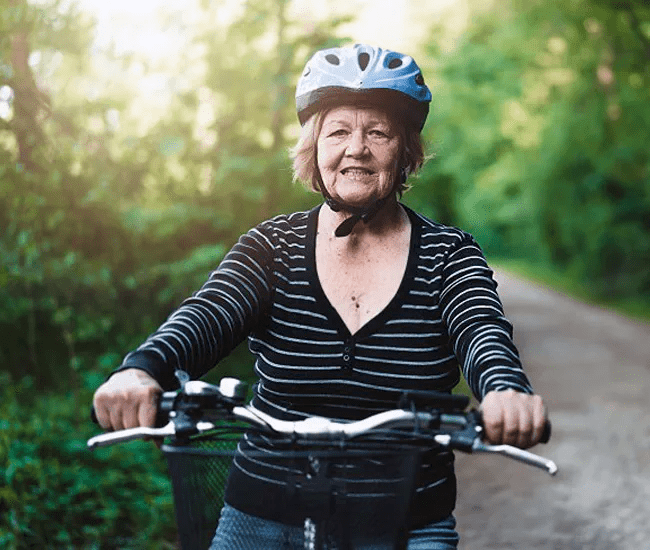 A senior woman rides her bike on a nature trail
