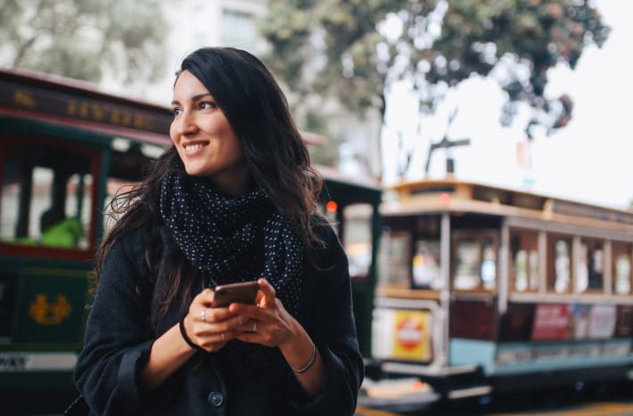 Una mujer en San Francisco, California, sonriendo frente a los tranvías