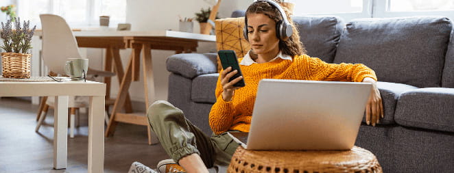 A woman talks on the phone while working on a laptop at home