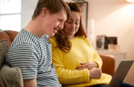 A woman and her child look at a laptop
