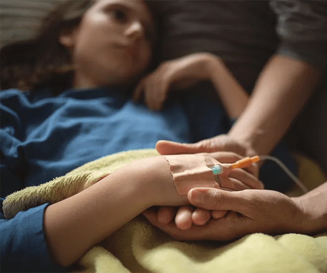 Una mujer joven se acuesta en una cama de hospital mientras alguien fuera de cuadro le sostiene la mano