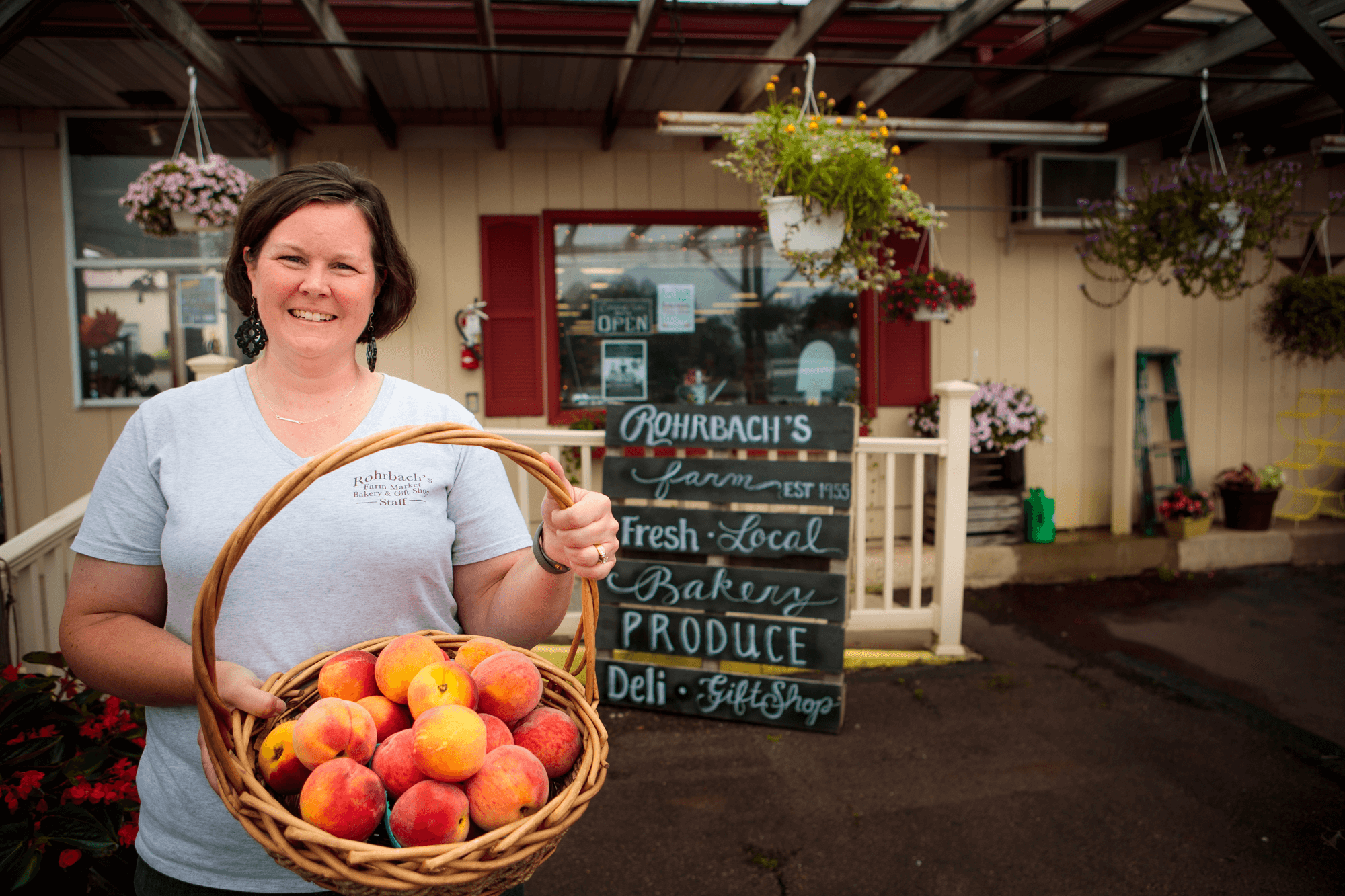 A local grocer holds up a basket of peaches in front of their store