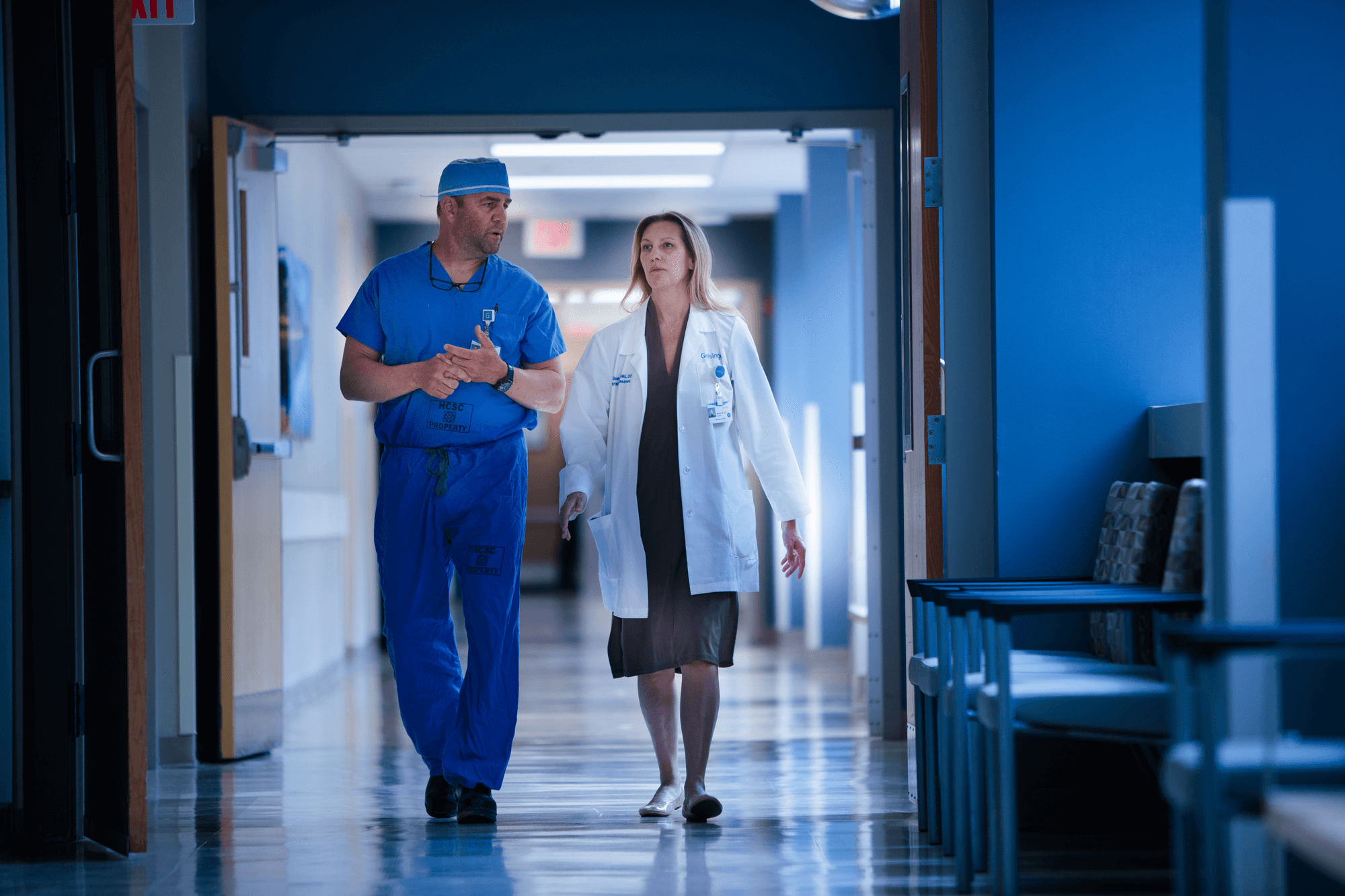 A surgeon and doctor chat while walking down a hospital hallway