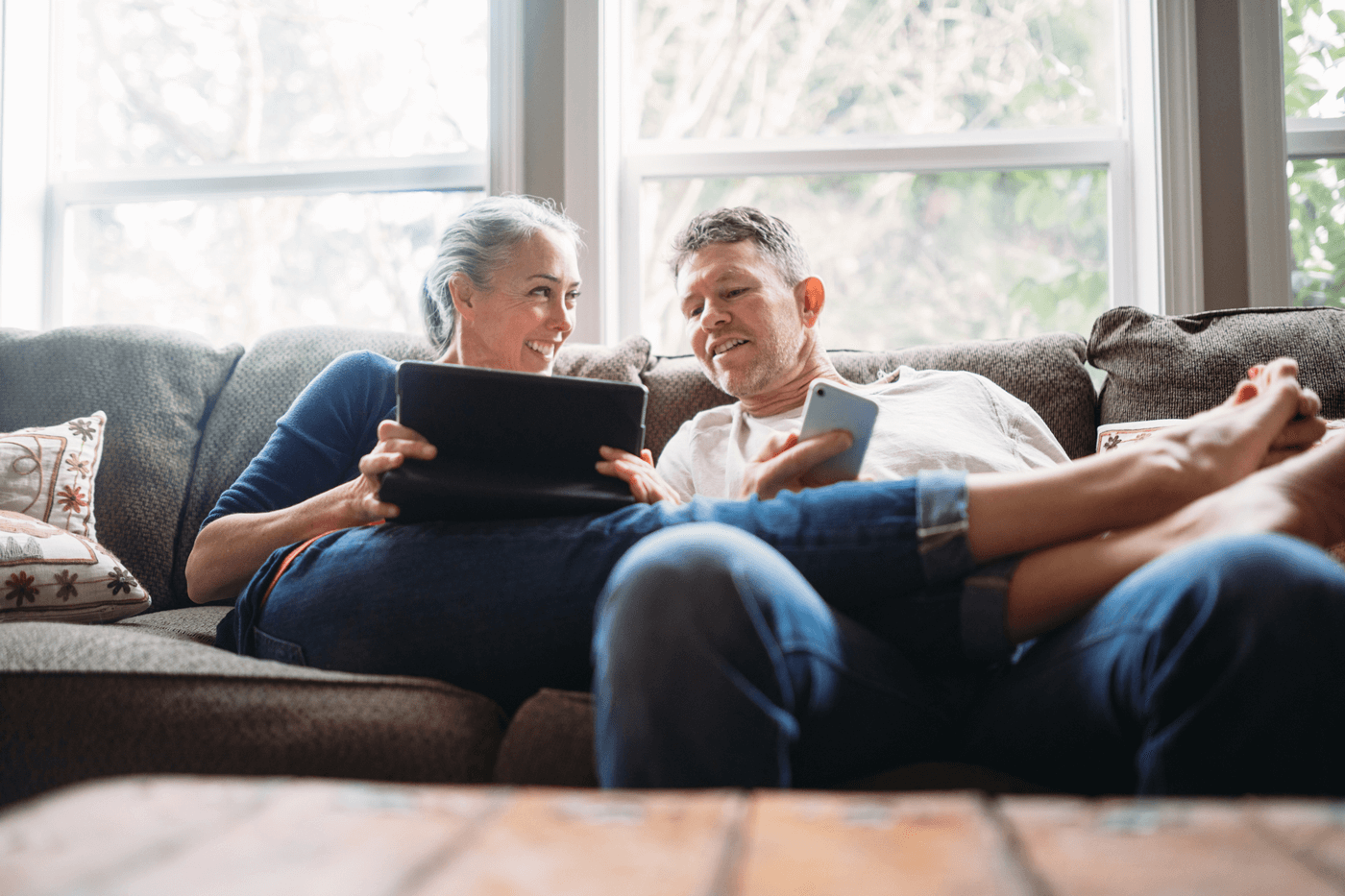 A senior couple sign paperwork on a tablet and phone
