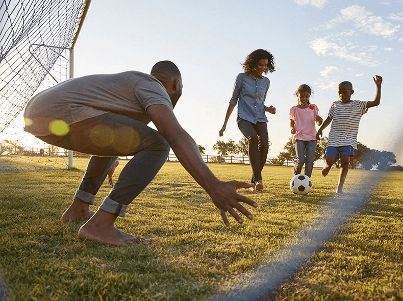 Una familia jugando al fútbol juntos en un parque