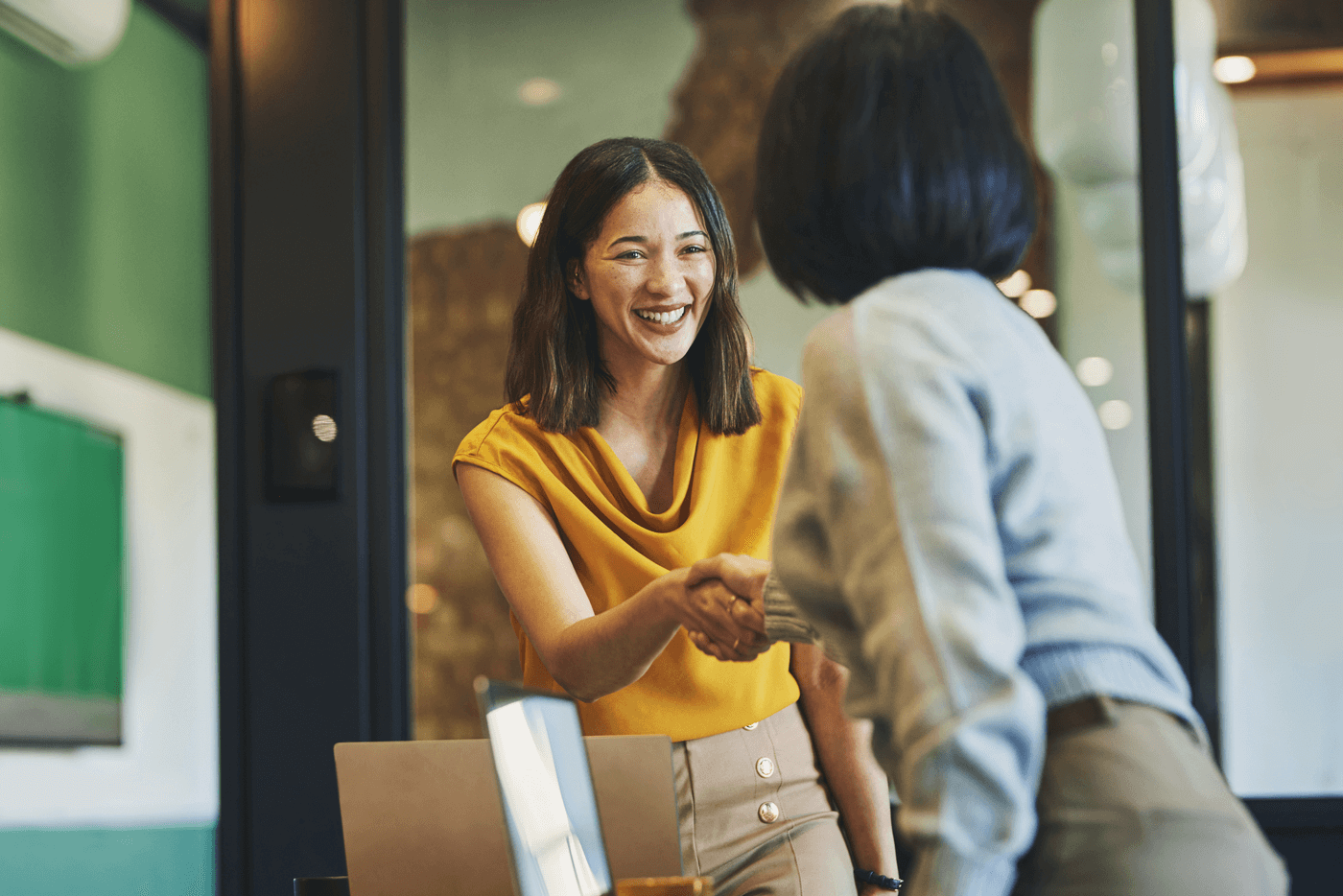 Two women shake hands in a business meeting