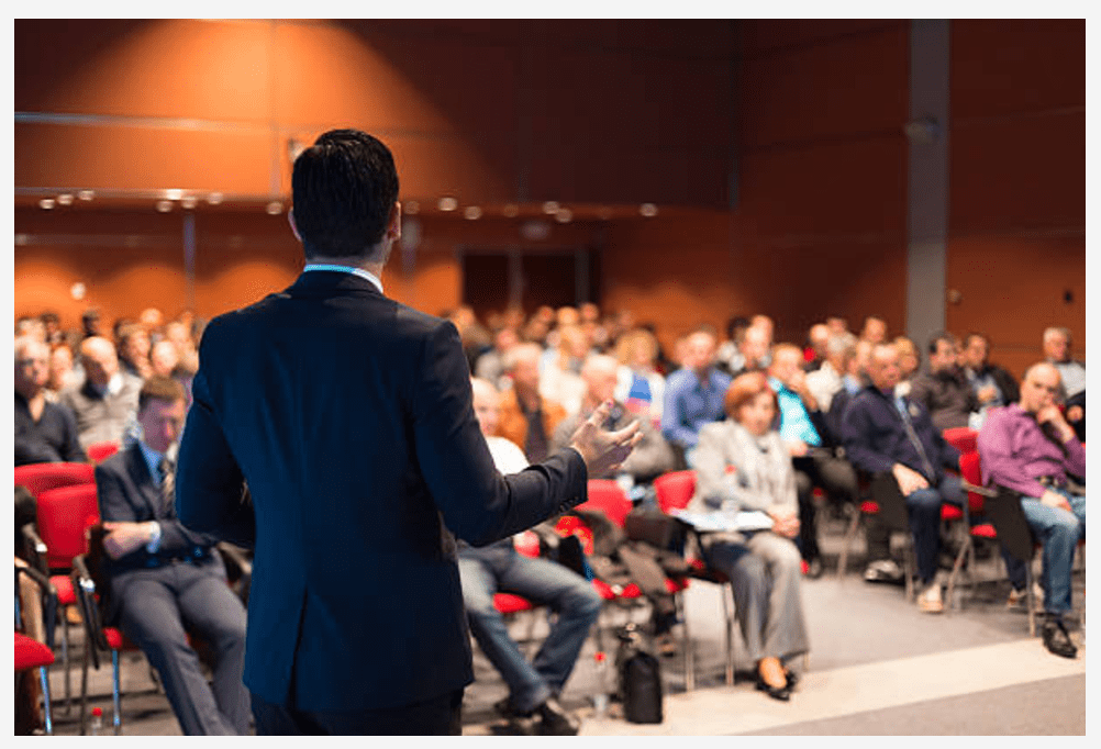 A man delivers a lecture to a group at a conference