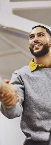 Hombre sonriendo y estrechando las manos con otra persona