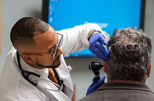 A nurse works with a patient in an examination room