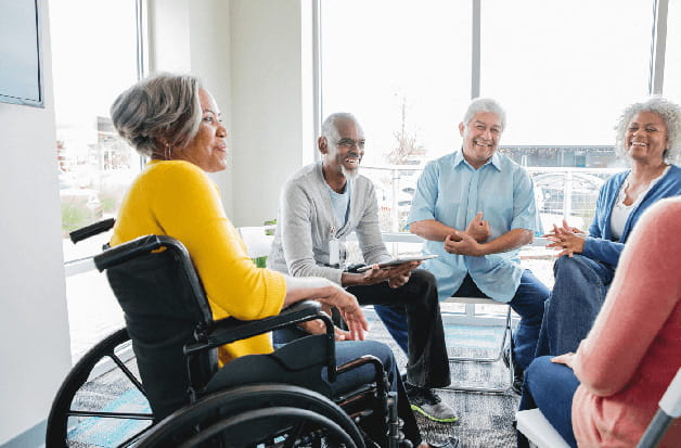 A senior in a wheelchair chats with a support group
