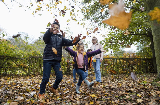 A group of children play with fallen leaves in autumn