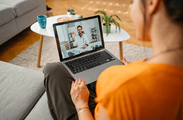 A patient talks to her doctor at home through her laptop