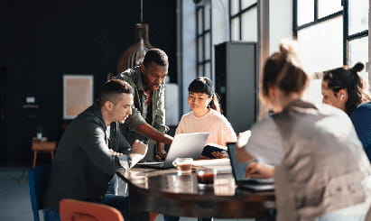 A group of coworkers gathered around a round table in an office