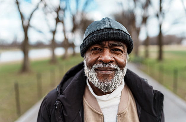 An older man standing in a field smiling