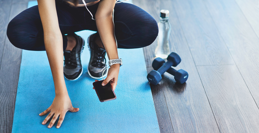 A woman checking her phone on a yoga mat