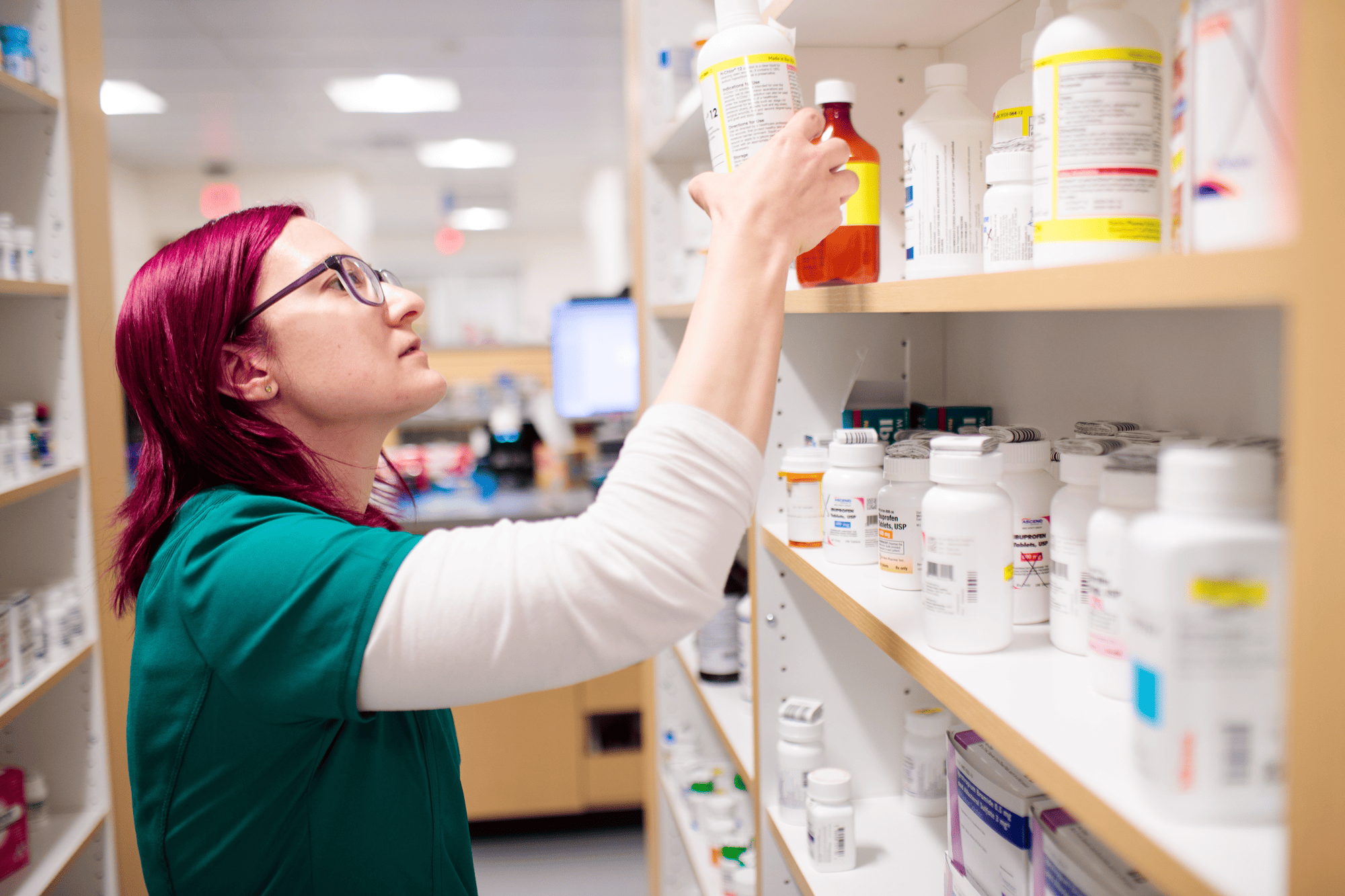 Un farmacéutico retira un medicamento recetado de un estante