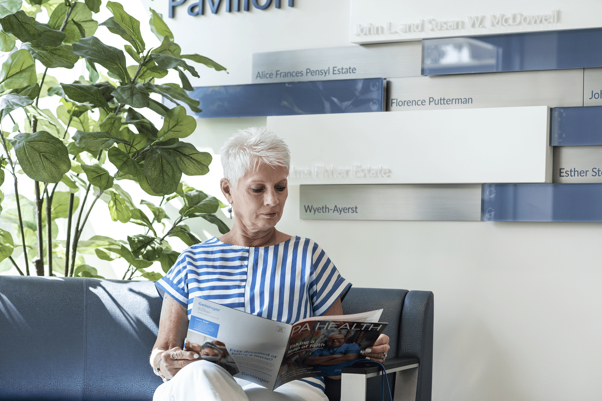An senior woman sits in a chair reading a magazine