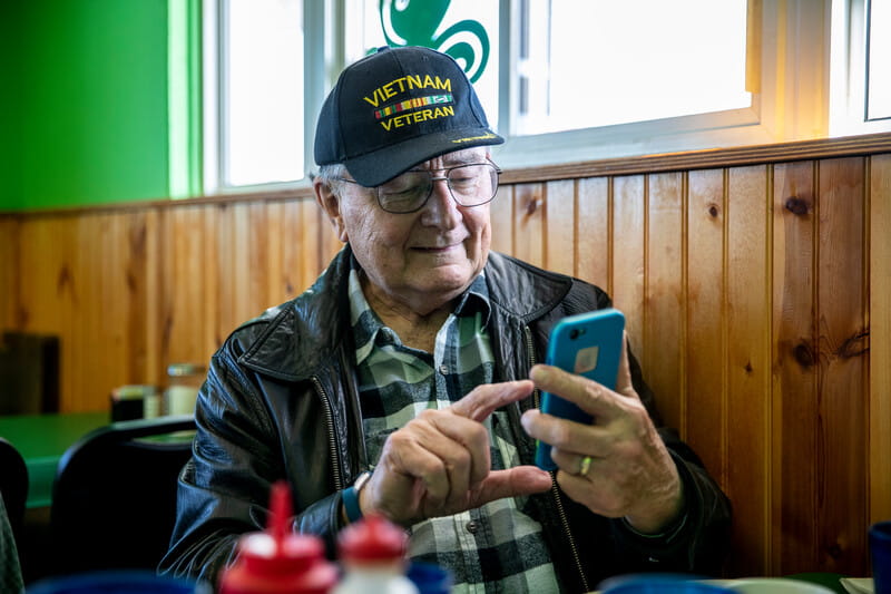 A veteran sitting in a diner and using a mobile phone.