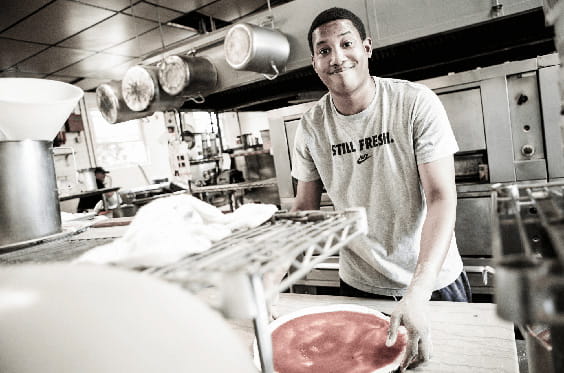 Un empleado que trabaja en una cocina preparando pizza