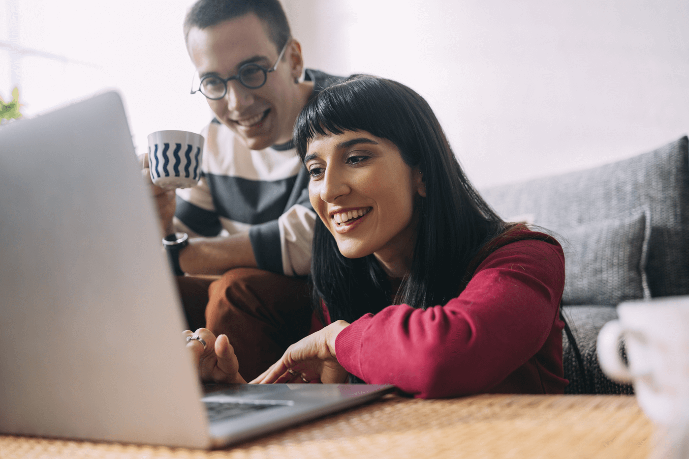 A young couple check their laptop at their couch