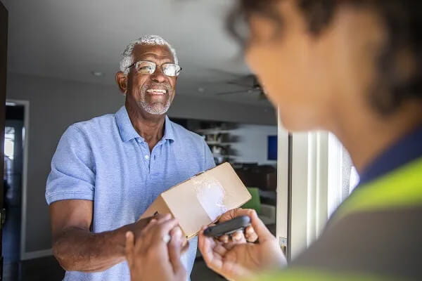 A senior receives a package from a delivery person