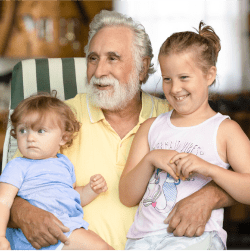 An elderly man sits with two young children